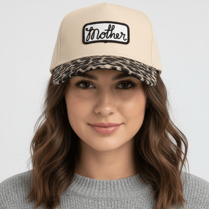 Woman wearing a beige cap with a leopard print bill against a white background